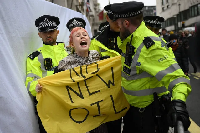 Police officers remove a climate activist protesting against the Rosebank oil field project in the North Sea off the coast of Scotland, outside the InterContinental London Park Lane hosting the Energy Intelligence Forum in central London on October 18, 2023. (Photo by Daniel Leal/AFP Photo)