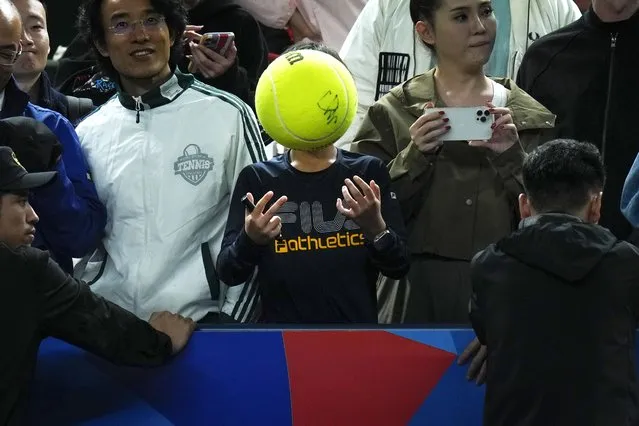 A boy throws a tennis ball as spectators wait for the arrival of retired tennis player Roger Federer during a Federer's fan day, a side event of the Shanghai Masters tennis tournament at Qizhong Forest Sports City Tennis Center in Shanghai, China, Friday, October 13, 2023. (Photo by Andy Wong/AP Photo)