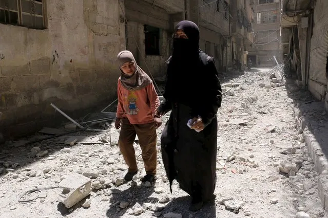 Residents walk upon the rubble of collapsed buildings after what activists said was shelling by forces loyal to Syria's President Bashar al-Assad at Ain Tarma in eastern Ghouta, a suburb of Damascus, Syria April 26, 2015. (Photo by Amer Almohibany/Reuters)