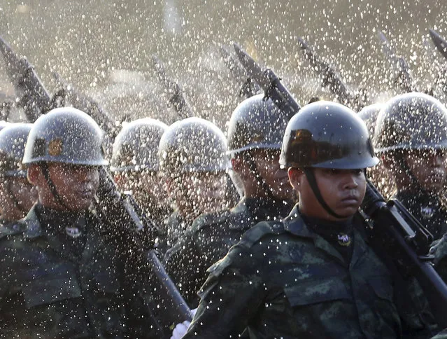 A Buddhist monk splashes holy water on to Thai soldiers during the Royal Thai Armed Forces Day ceremony at a military base in Bangkok, Thailand, Friday, January 18, 2019. (Photo by Sakchai Lalit/AP Photo)