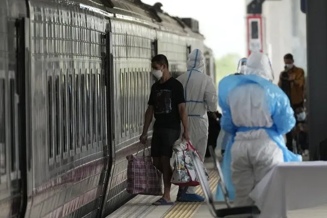 A man, who is among a group of people infected with COVID-19, gets into a train at Rangsit train station in Pathum Thani Province, Thailand to head to his hometown, Tuesday, July 27, 2021. Thai authorities began transporting some people who have tested positive with the coronavirus from Bangkok to their hometowns on Tuesday for isolation and treatment, to alleviate the burden on the capital’s overwhelmed medical system. (Photo by Sakchai Lalit/AP Photo)