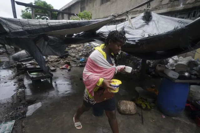 An earthquake-displaced person walks through a makeshift camp the morning after Tropical Storm Grace swept over Les Cayes, Haiti, Tuesday, August 17, 2021, three days after a 7.2-magnitude earthquake. (Photo by Fernando Llano/AP Photo)