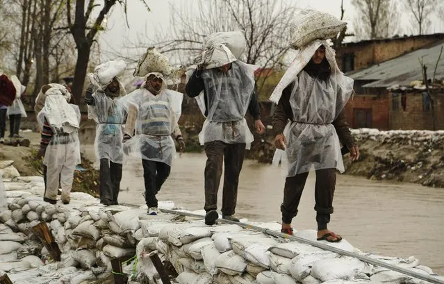 Laborers carry sand bags to repair a breach in an embankment in a flooded area of Srinagar, Indian-controlled Kashmir, Wednesday, April 1, 2015. Although flood waters were receding, residents in the main city of Srinagar were bracing for more trouble as the meteorological office has predicted more rain over the next few days. (Photo by Mukhtar Khan/AP Photo)