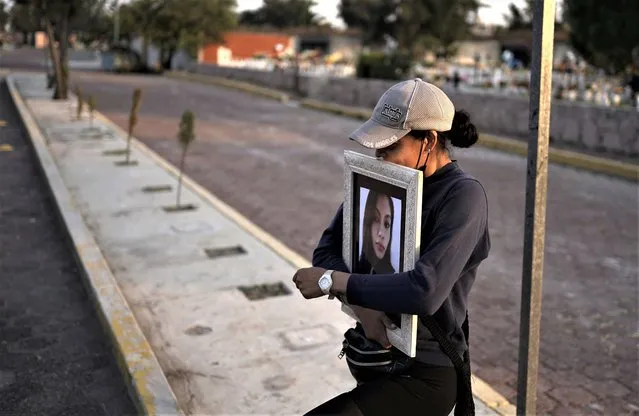 A friend of Monica Citlalli Diaz carries her photo on the sidelines of her funeral at a cemetery in Ecatepec, State of Mexico, Mexico, Friday, November 11, 2022. The 30-year-old English teacher became the ninth apparent femicide during an 11-day spate of killings in and around Mexico City from late October to early November. (Photo by Eduardo Verdugo/AP Photo)