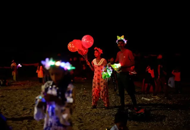 Vendors selling balloons and coloured lights wait for customers at a promenade on New Year's eve in Mumbai, India on December 31, 2023. (Photo by Francis Mascarenhas/Reuters)
