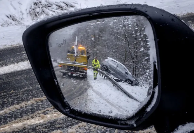 A view in a car mirror shows a car that veered off a country road near Frankfurt, Germany, Thursday, January 18, 2024, as heavy snow falls in many parts of Germany. (Photo by Michael Probst/AP Photo)