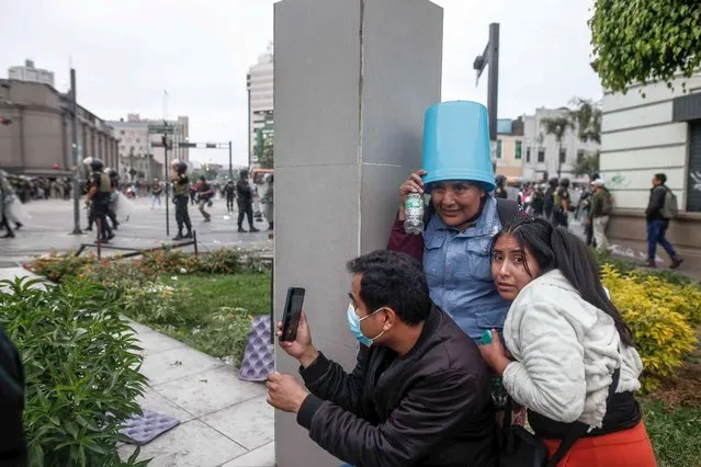 A group of people take shelter during clashes between protesters and police, on the outskirts of the Prefecture of Lima, where the now former president Pedro Castillo remains detained, in Lima, Peru, 07 December 2022. A small group of supporters and detractors of ousted Peruvian President Pedro Castillo clashed this 07 December in front of the center where the former president is being held in Lima, accused of attempting to carry out a self-coup. The Peruvian National Police (PNP) have had to intervene with tear gas and detain some of the protesters in order to cleary the central Alfonso Ugarte avenue. (Photo by Aldair Mejia/EPA/EFE/Rex Features/Shutterstock)