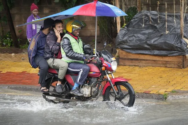 A motorbike carries passengers on a flooded road after heavy downpour in Nairobi Saturday, January 13, 2024. (Photo by Sayyid Abdul Azim/AP Photo)