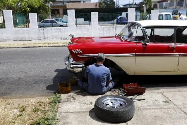 A man repairs a vintage car on a street in Havana city, Cuba, March 17, 2016. (Photo by Ivan Alvarado/Reuters)