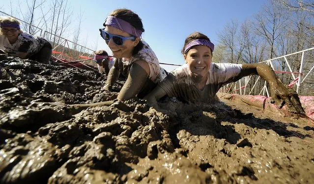 Teammates Shelbie Gilbert, of Dornsife, Pa., left, and Laura Bosack of Minersville, Pa., crawl through a mud pit obstacle on Saturday, May 2, 2015 during the Dirty Girl Mud Run at Montage Mountain in Scranton, Pa. (Photo by Butch Comegys/The Scranton Times-Tribune via AP Photo)