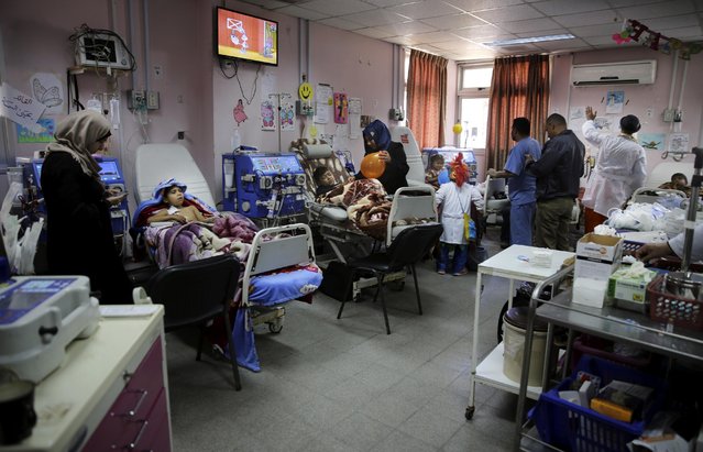 In this Thursday, March 17, 2016 photo, Palestinian clown doctors entertain children in the department of kidney diseases at Al-Rantisi children's hospital in Gaza City. Clown doctors Majed Kaloub, 24, and Alaa Miqdad, a 33-year-old dwarf, are employed by an international NGO into unusual places: hospitals, especially the pediatric ones; a game-changing shift that granted them steady work at best, but rendered them in need for psychosocial support as a side effect of the job. (Photo by Adel Hana/AP Photo)