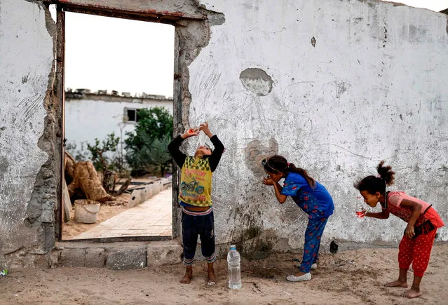 Palestinian children drink from plastic bottles filled with water drawn from a cistern in a poor neighbourhood in Khan Yunis in the southern Gaza Strip on October 24, 2018. The US nonprofit think- tank RAND corporation estimates that 97 percent of drinking water in the Gaza Strip is not drinkable by any recognized international standard, and that more than a quarter of illnesses and over 12 percent of child deaths in the past four years were due to water pollution. (Photo by Thomas Coex/AFP Photo)