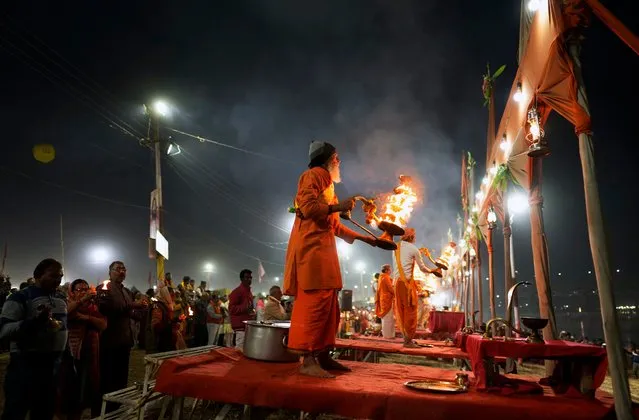 Hindu priests perform Aarti, a ritual involving circular movements of a traditional oil lamp, at Sangam, the confluence of rivers the Ganges and the Yamuna during Maghi Purnima or the full-moon day at the annual traditional fair in Prayagraj, in the northern state of Uttar Pradesh, India, Saturday, February 24, 2024. (Photo by Rajesh Kumar Singh/AP Photo)