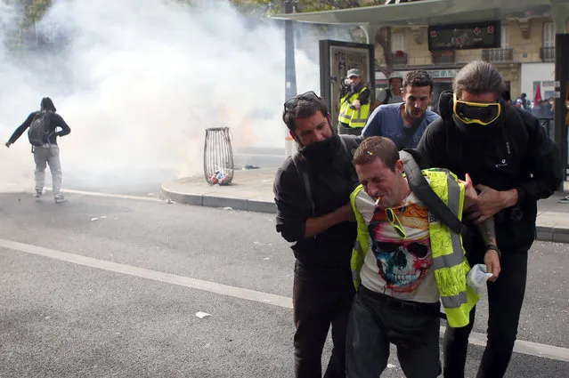 An injured demonstrator is helped during a May Day rally in Paris, Wednesday, May 1, 2019. Brief scuffles between police and protesters have broken out in Paris as thousands of people gather for May Day rallies under tight security measures. (Photo by Francois Mori/AP Photo)