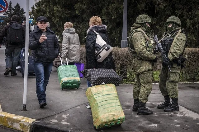 Armed men patrol the street outside Simferopol's airport in the Crimea region of Ukraine, on February 28, 2014. As the possibility of a showdown between Ukraine's fledgling government and the Kremlin appeared to grow Friday, armed men whose uniforms bore no insignia took up positions at the Simferopol and Belbek airports as Interior Minister Arsen Avakov warned of a direct provocation, but there was no sign of any violence. (Photo by Sergey Ponomarev/The New York Times)