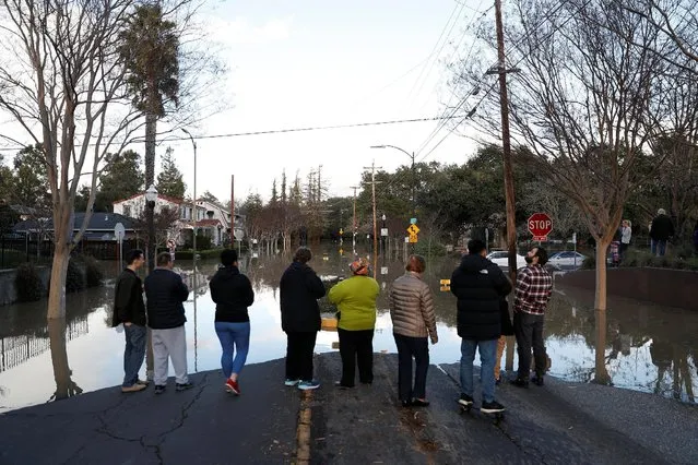 People stand by a flooded street near William Street Park after heavy rains overflowed nearby Coyote Creek in San Jose, California, U.S., February 21, 2017. (Photo by Stephen Lam/Reuters)