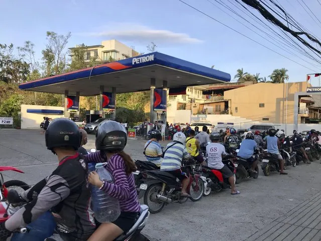 Residents line up for gasoline after Typhoon Rai damaged parts of Cebu city, central Philippines on Saturday, December 18, 2021. A strong typhoon engulfed villages in floods that trapped residents on roofs, toppled trees and knocked out power in southern and central island provinces, where more than 300,000 villagers had fled to safety before the onslaught, officials said. (Photo by Cheryl Baldicantos/AP Photo)