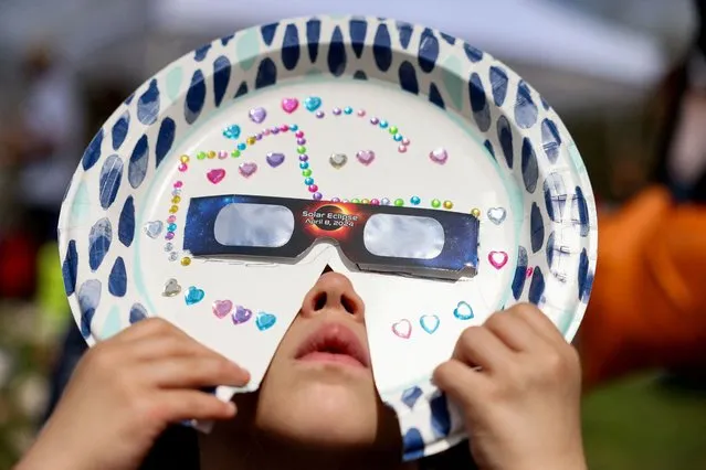 Sophia Moccia, 4, from Queens views a partial solar eclipse with a homemade mask, at New York Hall of Science in Queens borough, New York City, U.S., April 8, 2024. (Photo by Andrew Kelly/Reuters)