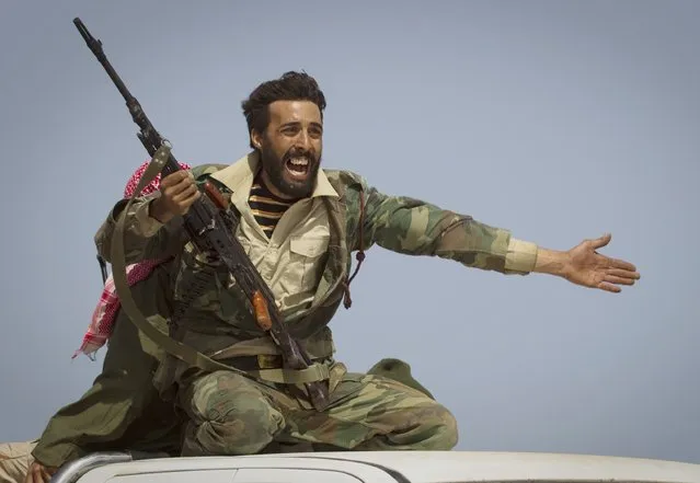 A Libyan rebel urges people to leave, as shelling from Gadhafi's forces started landing on the frontline outside of Bin Jawaad, 150 km east of Sirte, central Libya, Tuesday, March 29, 2011. (Photo by Anja Niedringhaus/AP Photo)