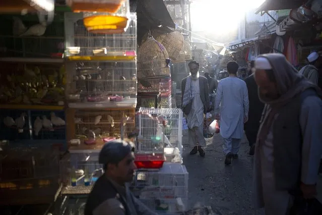 File - In this Tuesday, October 12, 2021 file photo, Afghans walk through a market in Kabul, Afghanistan. (Photo by Ahmad Halabisaz/AP Photo)