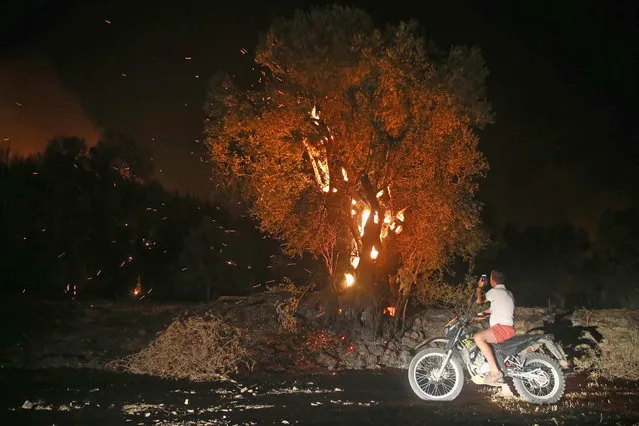 Flames and smoke rising as firefighters try to extinguish the fire that broke out at a forest in Mugla's Dalaman district, Turkey on July 11, 2019. Fire spread to Fethiye District's Gocek neighborhood due to wind. (Photo by Orhan Cicek/Anadolu Agency/Getty Images)