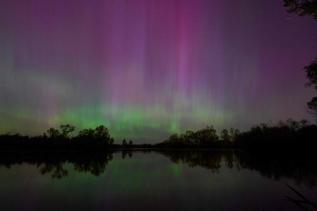 Northern lights or aurora borealis illuminate the night sky near London, Ontario, during a geomagnetic storm on May 10, 2024. The most powerful solar storm in more than two decades struck Earth on May10, 2024, triggering spectacular celestial light shows in skies from Tasmania to Britain – and threatening possible disruptions to satellites and power grids as it persists into the weekend. Auroras are often observed in Canada's northern regions, but rarely in southern Ontario. (Photo by Geoff Robins/AFP Photo)