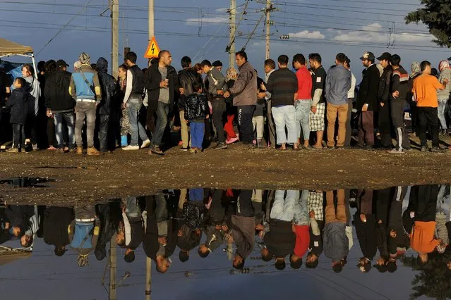 People are reflected in a puddle next to tents following heavy rainfall at a makeshift camp for migrants and refugees at the Greek-Macedonian border near the village of Idomeni, Greece, April 24, 2016. (Photo by Alexandros Avramidis/Reuters)