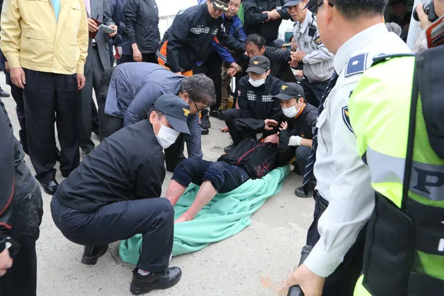 A rescued passenger from a ferry sinking off South Korea's southern coast, is carried by police and rescue teams on his arrival at Jindo port in Jindo, south of Seoul, South Korea, Wednesday, April 16, 2014. (Photo by Park Chul-heung/Reuters/Yonhap)