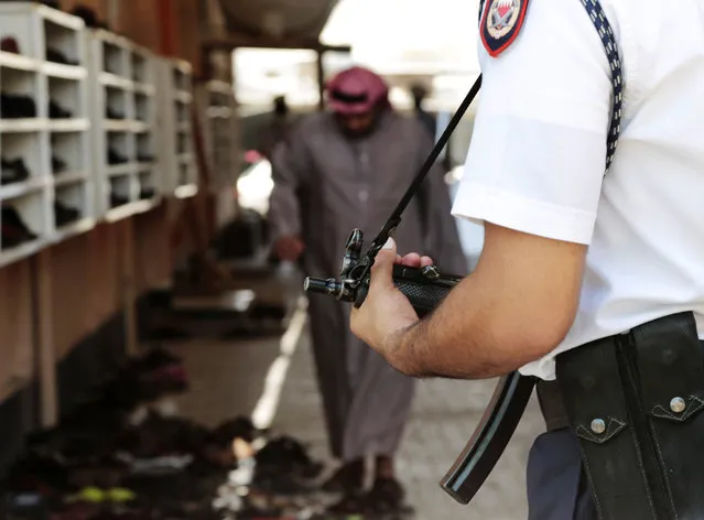 A Bahraini police officers stands guard outside of Shiite Muslim mosque ahead of mid-day prayers during the holy month of Ramadan in the western village of Karzakan, Bahrain, Friday, July 3, 2015. Bahraini government and religious authorities are taking extra precautions in the wake of suicide bombing attacks on Shiite mosques in neighboring Saudi Arabia and Kuwait that were claimed by the Islamic State group and killed dozens of people. (Photo by Hasan Jamali/AP Photo)