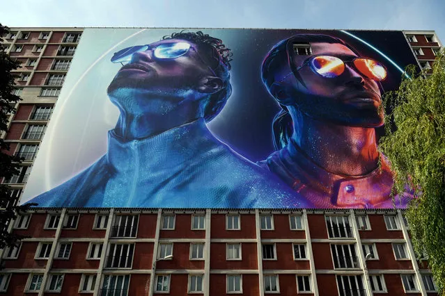 This picture taken on August 28, 2019 shows a giant banner depicting the two brothers Ademos and N.O.S (Tarik and Nabil Andrieu) of the French rap group PNL (Peace N' Loves), set up on a building where the two artists spent a part of their adolescence, in the Youri Gagarine quarter in Ivry-sur-Seine on the outskirts of the French capital Paris. Some see it as “the end of a world”, others “a page that turns”: the destruction of the emblematic workers' quarter Gagarine, at the gates of Paris, emblem of the red suburbs, arouses the nostalgia and apprehension of residents who attend the entrance of their city in the era of Greater Paris. Inaugurated in 1963 in the presence of Russian space pioneer Yuri Gagarin – just two years after he became the first person in space – the “Cite Gagarine” underscored the Communist Party's appeal in much of postwar France. (Photo by Lionel Bonaventure/AFP Photo)