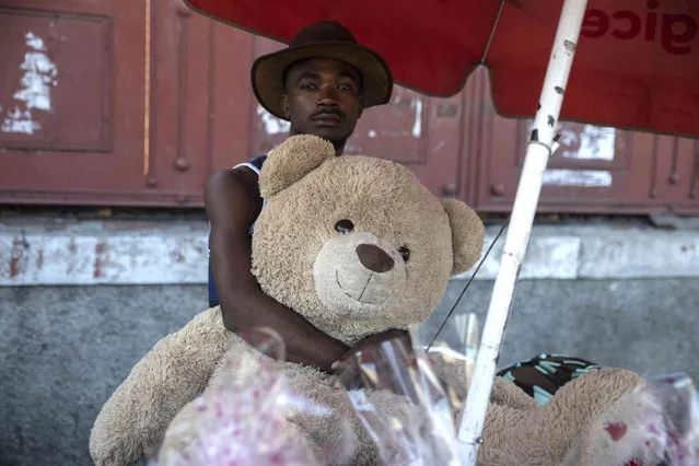A vendor holds a teddy bear for sale on Valentine's Day in Port-au-Prince, Haiti, Monday, February 14, 2022. (Photo by Joseph Odelyn/AP Photo)
