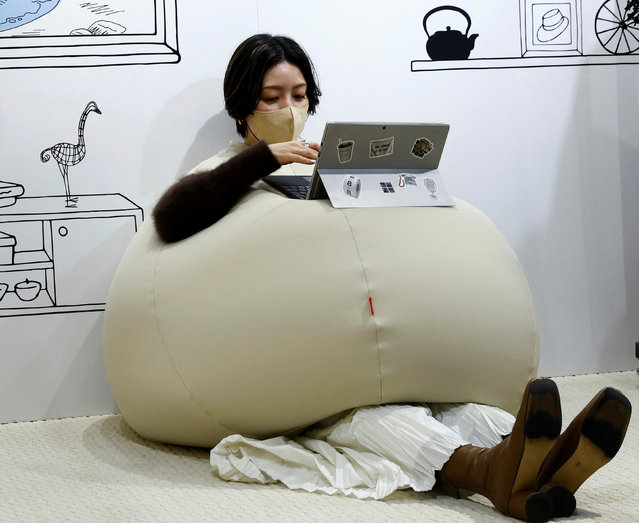 Yuu Matsuzaki, a product buyer for the Marui Group uses her laptop on the wearable beanbag during a photo opportunity at a pop-up booth of the Shinjuku Marui main department store in Tokyo, Japan on February 6, 2023. While the beanbag's onion-shaped goofy style made it a hit on Japanese social media earlier this month, the main goal was relaxation, according to Shogo Takikawa, a representative of the beanbag's manufacturer, Takikou Sewing. (Photo by Kim Kyung-Hoon/Reuters)