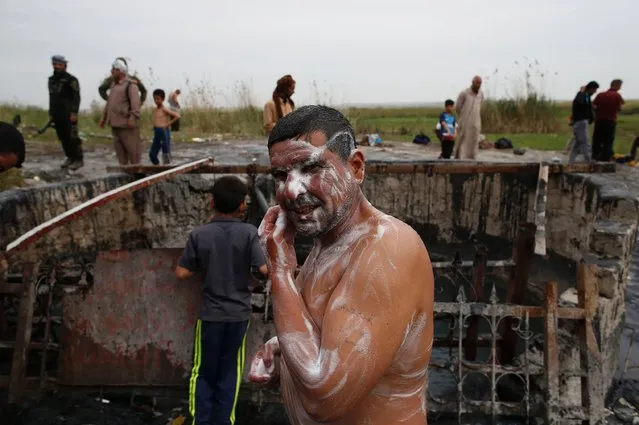 Iraqis bathe in a sulphur pond in the Hamam al-Alil area, about 14 kilometres from the southern outskirts of Mosul, on April 1, 2017. More than 200,000 people have fled west Mosul since the operation to oust the Islamic State group began last month, and officials and witnesses say that air strikes have taken a devastating toll on civilians who remained in the city. (Photo by Ahmad Gharabli/AFP Photo)