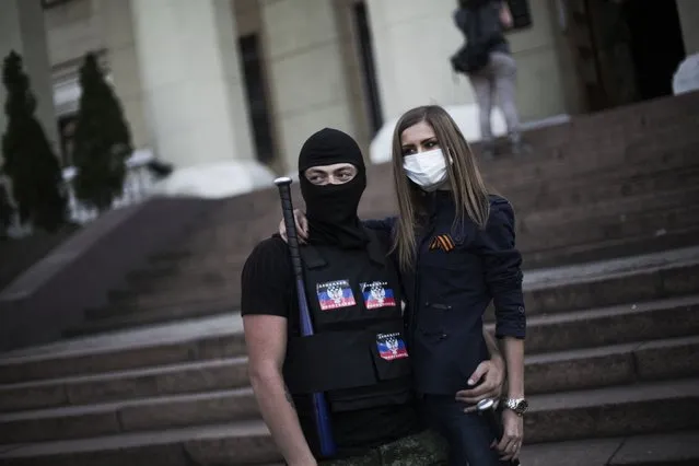 Masked pro-Russia militants stand outside a local television broadcasting center after storming it in Donetsk, Ukraine, Sunday, April 27, 2014. A crowd of hundreds of pro-Russia activists stormed the television broadcasting center in Donetsk, the regional capital of eastern Ukraine, to demand that Russian state channels be put back on the air. The Kiev government last month blocked the broadcasts of the Russian channels, which serve as propaganda tools for the Kremlin. (Photo by Manu Brabo/AP Photo)