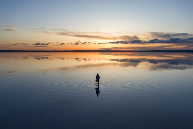 An aerial view of a man standing on Lake Tuz, Turkiye's second largest lake, during sunset in Ankara, Turkiye on April 22, 2024. The lake, which is on the UNESCO World Heritage Tentative List with its unique natural structure, welcomes many local and foreign tourists every year as it provides 70 per cent of the country's salt needs. (Photo by Hakan Nural/Anadolu via Getty Images)