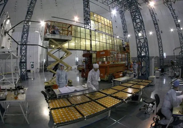 Specialists of the “Kvant” (Quantum) research-and-production enterprise work on a solar battery for the Express AM6 new generation geostationary telecommunications heavy satellite at the large-sized transformed mechanical systems centre of the Reshetnev Information Satellite Systems company in the Siberian town of Zheleznogorsk, some 50 km (31 miles) northeast of Krasnoyarsk, April 2, 2014. (Photo by Ilya Naymushin/Reuters)