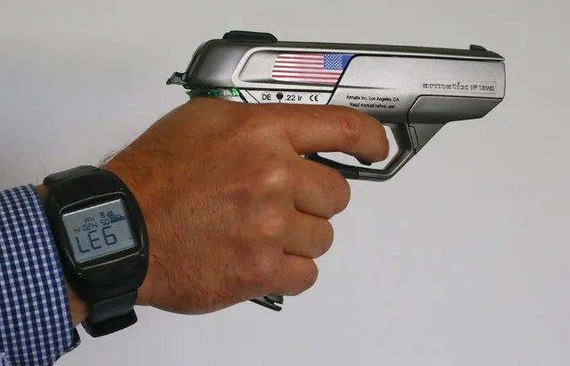 An Armatix employee holds a “smart gun” by the company at the Armatix headquarters in Munich May 14, 2014. The gun is implanted with an electronic chip that allows it to be fired only if the shooter is wearing a watch that communicates with it through a radio signal. If the gun is moved more than 10 inches (25 cm) from the watch, it will not fire. (Photo by Michael Dalder/Reuters)