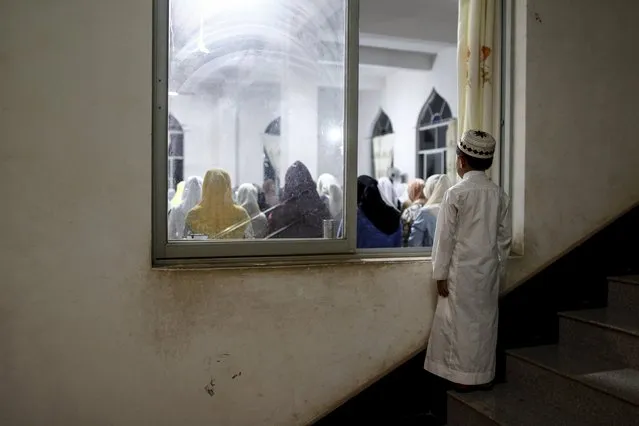 A boy looks in through a window as he and other worshippers pray on Laylat al-Qadr during the Muslim holy month of Ramadan, at a mosque on the outskirts of Kunming, Yunnan province, China, July 13, 2015. (Photo by Wong Campion/Reuters)