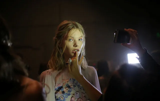 A model for We Are Kindred has makeup applied by mobile phone light back stage during Fashion Week Australia in Sydney on May 17, 2017. (Photo by Steven Saphore/Reuters)