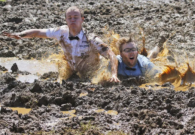 Players celebrate winning a match during the German Mud Soccer  Championships in Rieste, Germany, Saturday, May 31, 2014. Some 1,000 participants from all over Germany compete in three categories, men, women and mixed for the German Championship titles.  (Photo by Frank Augstein/AP Photo)