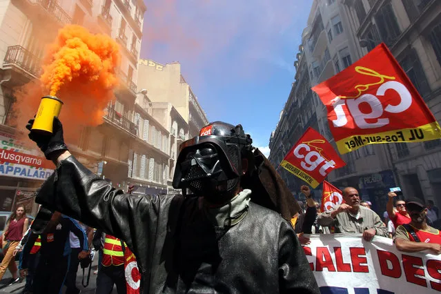 A steelworker from the ArcelorMittal steel plant in Fos-sur-Mer wearing a mask of Darth Vader, burns flares during a demonstration in Marseille, southern France, Thursday, June 2, 2016. Several thousand protestors are demonstrating during a day of strikes and protest against the law job government reform. (Photo by Claude Paris/AP Photo)