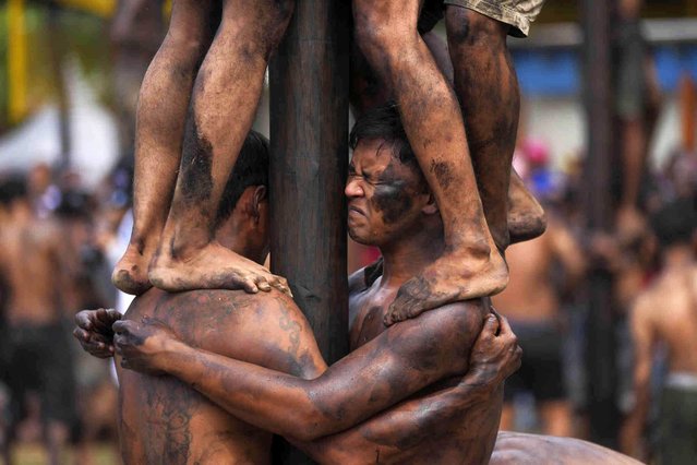 A participant bears the weight of other men above him as people climb on greased poles to retrieve prizes in a greased-pole climbing competition during the 79th Independence Day anniversary at Ancol Beach in Jakarta, Indonesia, Saturday, August 17, 2024, celebrating its independence from the Dutch colonial rule. (Photo by Tatan Syuflana/AP Photo)