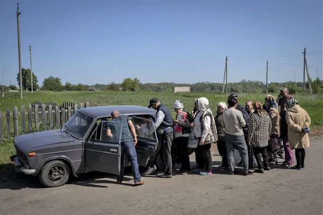 Villagers queue to buy cigarettes and bread from a peddler in the village of Staryi Saltiv, east Kharkiv, Ukraine, Friday, May 20, 2022. The village formerly occupied by Russian forces is back under Ukrainian control, albeit very close to the front line and under constant shelling. (Photo by Bernat Armangue/AP Photo)