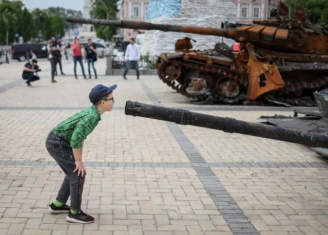 A boy looks at a destroyed Russian infantry fighting vehicle during an exhibition displaying destroyed Russian military vehicles, amid Russia's invasion, in central Kyiv, Ukraine on May 21, 2022. (Photo by Gleb Garanich/Reuters)
