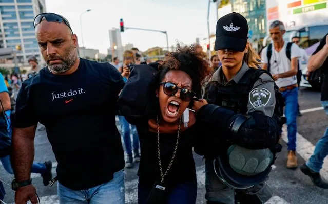 Members of the Israeli security forces detain a protester during a demonstration in Tel Aviv on July 3, 2019, against police violence and the recent killing of a young man. Israel braced for a third day of protests after an off-duty police officer killed a young man of Ethiopian origin, as Israeli leaders urged calm amid accusations of racism. In areas throughout the country since July 1, protesters have blocked roads, burned tyres and denounced what they see as discrimination against the Ethiopian-Israeli community. Police say 136 people have been arrested and 111 officers have been wounded, many injured by stones, bottles and petrol bombs thrown at them. (Photo by Ahmad Gharabli/AFP Photo)