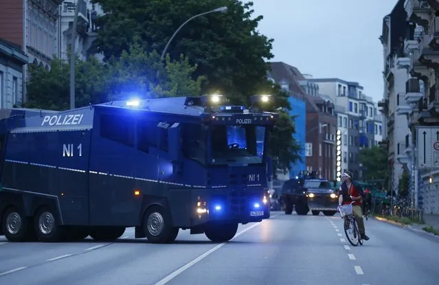 A person cycles past a water cannon near Schanzenviertel ahead the G20 summit in Hamburg, Germany, July 4, 2017. (Photo by Hannibal Hanschke/Reuters)