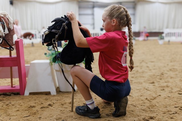 Competitors wait to take part in the UK Hobby Horse championship at Bury Farm Equestrian Centre on September 08, 2024 in Slapton, United Kingdom. While hobby horsing as a form of play has been around for centuries, the modern-day interpretation of the sport originated in Finland. Hobby horse competitions feature young enthusiasts trotting, galloping, and cantering on toy horses in various disciplines such as jumping and dressage. Its popularity has surged in recent years, especially during covid, and is growing in appeal. Young equine enthusiasts take advantage of its inclusivity, and enjoy the physical activity required, creativity and freedom of expression. The sport has also been found to help young people suffering with autism and ADHD, giving them a chance to connect with other young people with a love of horses. (Photo by Dan Kitwood/Getty Images)