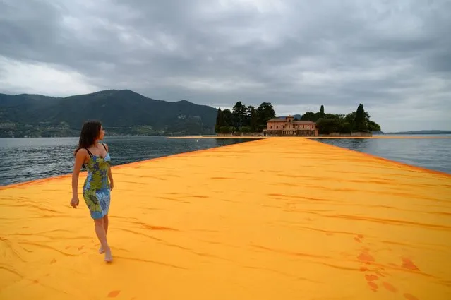 A woman walks on the monumental installation “The Floating Piers” created by artist Christo Vladimirov Javacheff and Jeanne-Claude, on June 16, 2016 during a press preview at the lake Iseo, northern Italy. (Photo by Filippo Monteforte/AFP Photo)