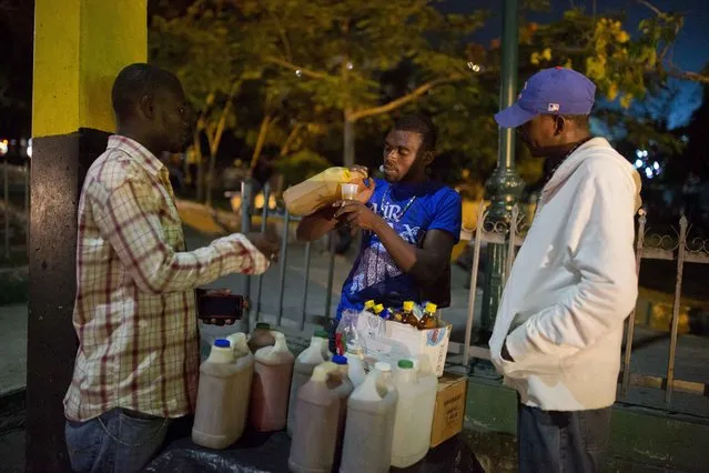 In this June 23, 2017 photo, Smith Nazon, 29, sells clairin, a sugar-based alcoholic drink, on the sidewalk in Petion-Ville, Haiti. A 1 liter bottle sells for about $1.36 dollars, about one-eighth the price of the least expensive bottle of Barbancourt rum, Haiti's most famous export. (Photo by Dieu Nalio Chery/AP Photo)