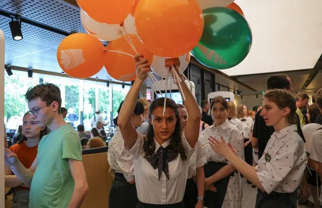 An employee carries balloons at the new restaurant “Vkusno & tochka”, which opens following McDonald's Corp company's exit from the Russian market, in Moscow, Russia on June 12, 2022. (Photo by Evgenia Novozhenina/Reuters)